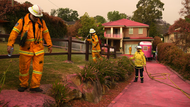 Firefighters clean up in Turramurra after fire retardant was dropped from a plane on Tuesday. 