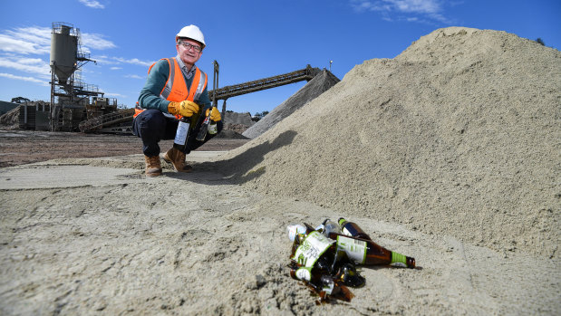 The firm's general manager recycling industries Mark Barraclough with glass bottles before and after being processed in a pile of sand.  