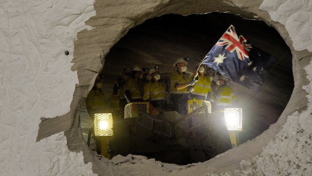A worker on one of the two roadheaders waves the Australian flag moments after smashing through sandstone connecting two sections of the M4-M5 Link.