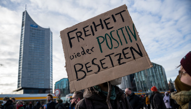 People with posters saying "Re-occupying freedom in a positive way" are protesting prior to a rally in Leipzig, Germany.