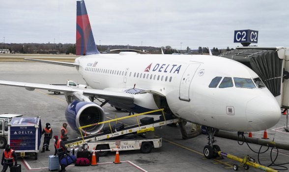 Employees wearing protective face masks unload a Delta.