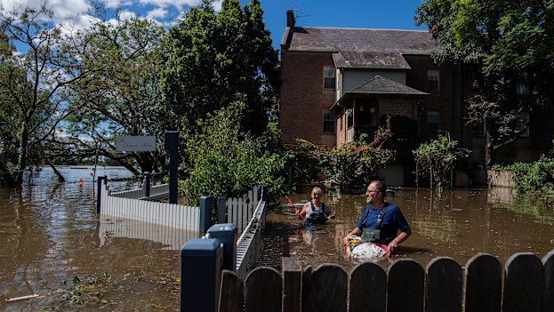 John and Sue Brookes cleaning up floating debris in the backyard of their Thompson Square home in Windsor. 