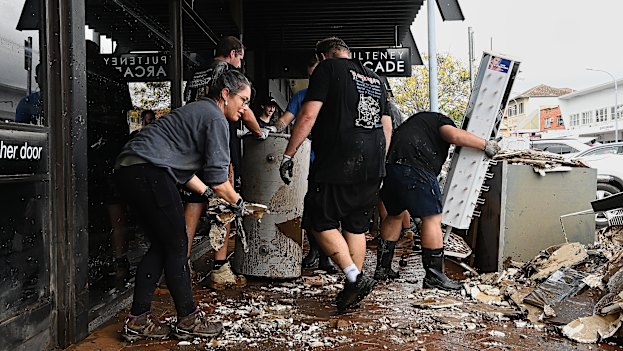 Residents clear up the debris after flooding in Taree last year.