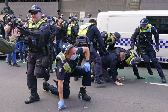 Police officers detain a man as protesters gather outside Victoria's Parliament House on Sunday.