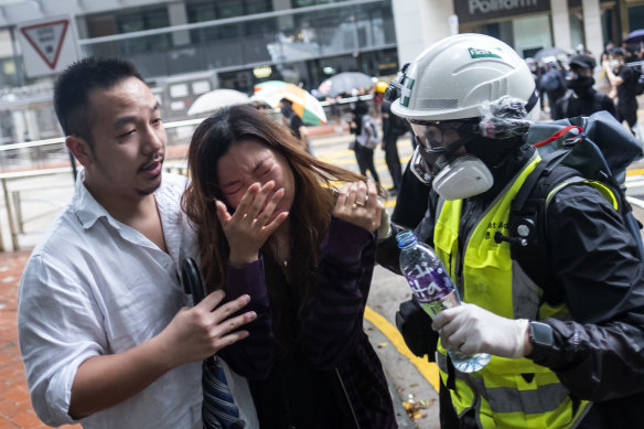A first aid volunteer assists a pedestrian affected by tear gas during a protest on Queensway.