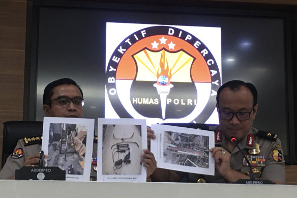 Indonesian National Police spokesperson Brigadier General Dedi Prasetyo, right, and an aide show photos of items confiscated during anti-terror raids.
