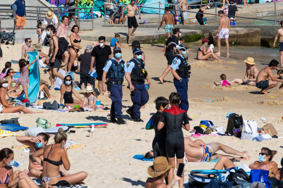 Masked police amid the unmasked crowds on Bondi Beach last Sunday.
