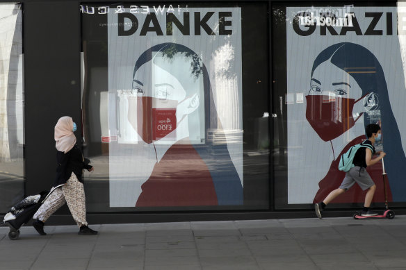 Masks forever? A woman and child wearing face masks pass face mask posters on Oxford Street, central London. 