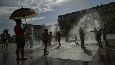 People cool off in a fountain during a hot summer day, in Pamplona.