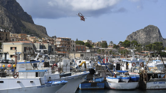 An Italian Firefighters helicopter flies over the harbor of Porticello, southern Italy.