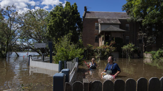 John and Sue Brookes cleaning up floating debris in the backyard of their Thompson Square home in Windsor. 