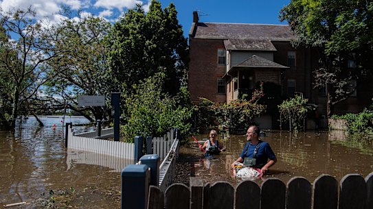John and Sue Brookes cleaning up floating debris in the backyard of their Thompson Square home in Windsor. 