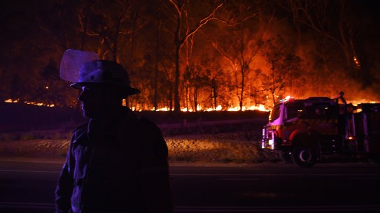 A RFS fire fighter with the Charmhaven unit monitors a small flare-up on New Year's Day on the Kings Highway near Batemans Bay.