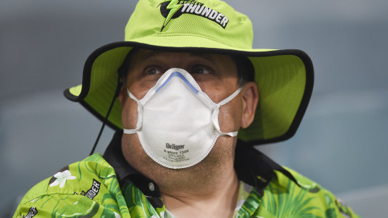 A fan wears a face mask as protection from the smoke at Manuka Oval. 