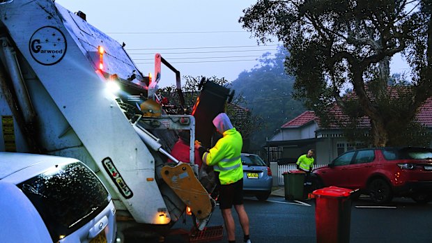 Men load rubbish into a truck that collects residential waste along Macauley street in Leichhardt.