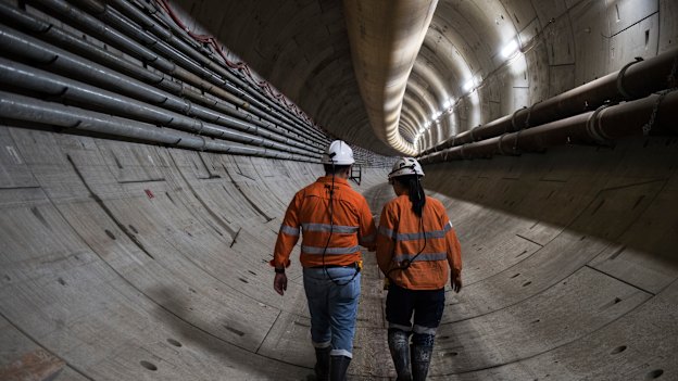 Construction workers walk through one of the 800-metre-long twin tunnels carved out of rock and sediment beneath Sydney Harbour. 