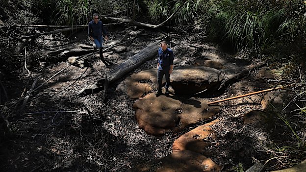 UNSW Professor William Glamore (left) and PhD candidate Joe Cairns at the bottom of a dried-up waterfall and pond under Swamp 14.