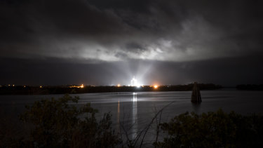 A SpaceX Falcon 9 rocket with the company's Crew Dragon spacecraft onboard is seen illuminated by spotlights on the launch pad in Florida.