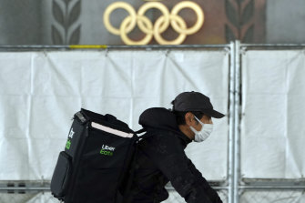 An Uber Eats delivery person carries items near the Japan National Stadium.