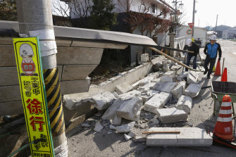Men help clean debris after the wall of a house collapsed in Kunimi town, north of Fukushima city, north-eastern Japan.