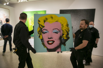 Shot Sage Blue Marilyn being carried into the Christie’s showroom on Sunday. The artwork sold for $US195 million on Monday.