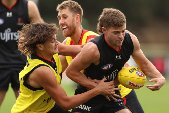 Brayden Ham is challenged by Tex Wanganeen and Dyson Heppell during Essendon’s training session.