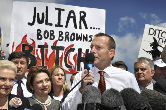 Then Opposition Leader Tony Abbott addresses the crowd during a demonstration against the Labor government’s proposed carbon tax in 2011 with anti-Gillard signs in the background.