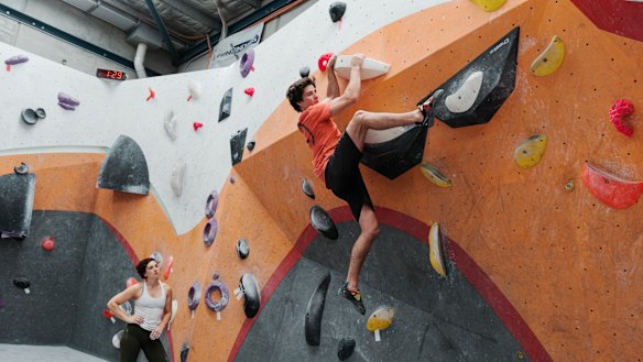 Up and away: Emma Horan watches Ben Abel complete at a practice climb at Nomad Bouldering in Annandale.