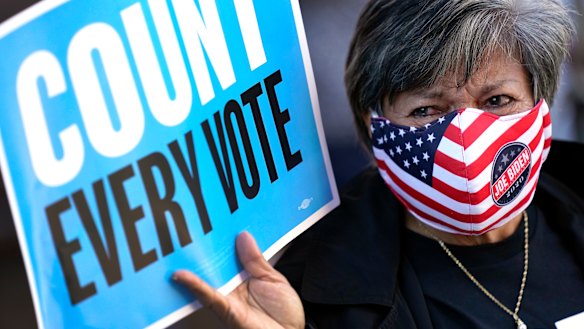 A volunteer election poll worker joins demonstrators as they stand across the street from the federal courthouse in Houston.