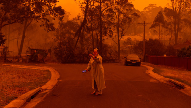 A resident of Mogo, on the NSW South Coast, outside her neighbours' property after fire engulfed the town.