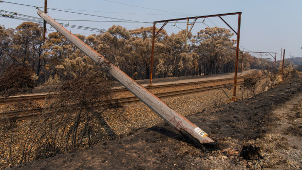 A burnt power pole fallen across the rails along the Blue Mountains Line,  near Dargan.