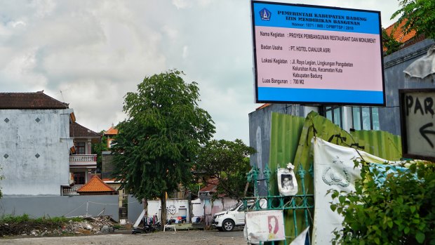 A building permit sign for a 700-sqm building on the 800-sqm site was placed above fading photos of the bombing victims at the former Sari Club site in Bali on Wednesday.