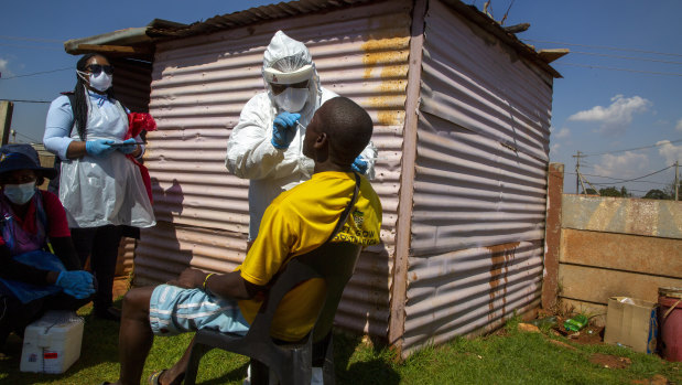 Health workers collects samples for coronavirus testing outside a shack to combat the spread of COVID-19 at Lenasia South, Johannesburg, South Africa.