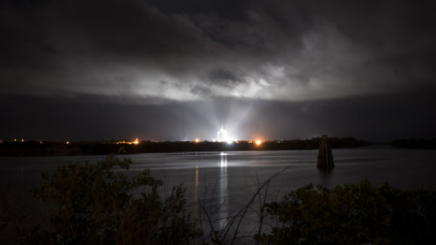 A SpaceX Falcon 9 rocket with the company's Crew Dragon spacecraft onboard is seen illuminated by spotlights on the launch pad in Florida.