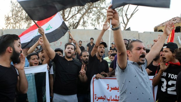 Demonstrators wave national flags and chant slogans during a demonstration demanding better public services in Basra on Tuesday.