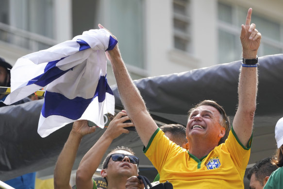 Bolsonaro holds an Israeli flag on Sunday. He and some of his former aides are under investigation into allegations they plotted a coup to remove his successor, Lula, who is at odds with Israel over Gaza.
