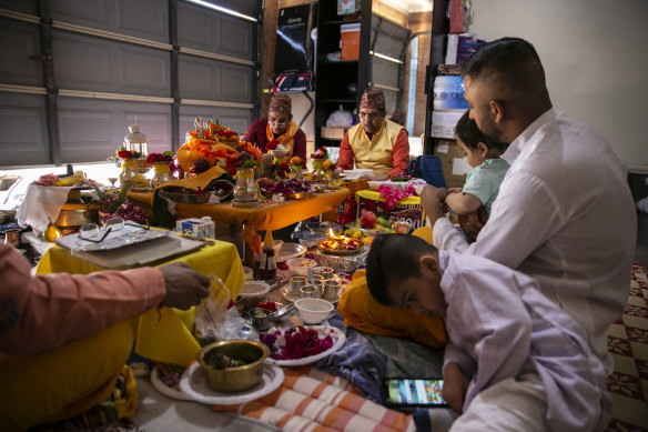 Keshav (in white) and Manita (in red), 27 sitting around a puja ceremony in their garage