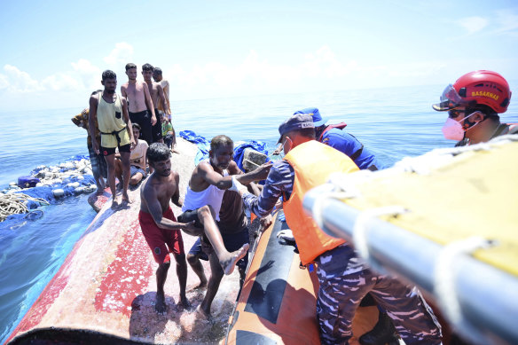Rohingya refugees climb onto a rescue boat off West Aceh on Wednesday.