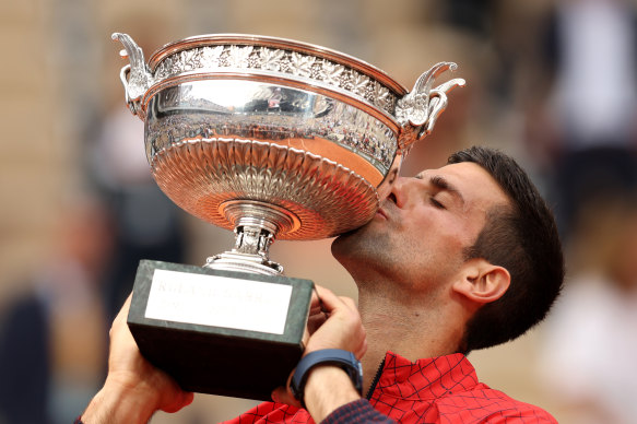 Novak Djokovic kisses the French Open trophy for a third time.