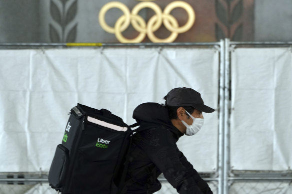 An Uber Eats delivery person carries items near the Japan National Stadium.