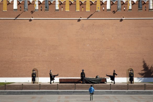 A man watches as the Kremlin guards change at the Tomb of Unknown Soldier in almost empty Alexander's Garden at the Kremlin Wall in Moscow, on state holiday, May 1.