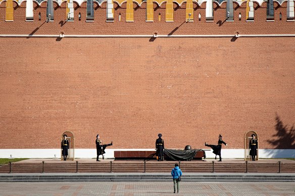 A man watches as the Kremlin guards change at the Tomb of Unknown Soldier in almost empty Alexander's Garden at the Kremlin Wall in Moscow, on state holiday, May 1.