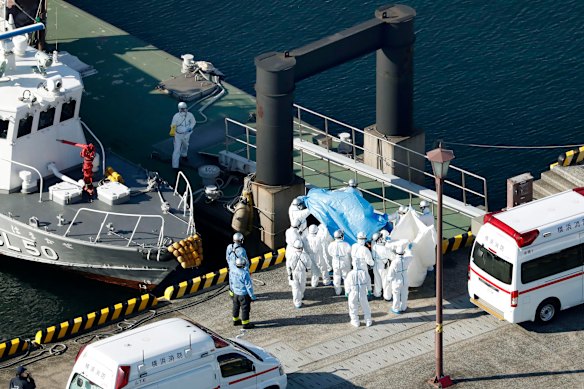 Medical workers in protective suits lead a passenger tested positive for a new coronavirus from the cruise ship Diamond Princess at Yokohama.