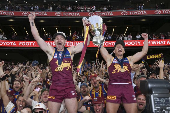 Lachie Neale and Dayne Zorko celebrate with the premiership cup.