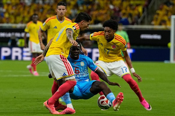 Congo’s Ngalayel Mukau (6) falls to the ground in a clash with Colombia’s Gustavo Puerta (14) and Johan Mojica (17).