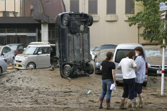 A car stands vertically on a muddy road after being washed away by flood, in Hitoyoshi, Kumamoto prefecture.