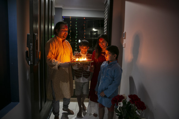 Ram with wife Iswara and their two young sons hold up candles at their doorstep to for Hindu Diwali at their home in Caddens in the Penrith LGA. 