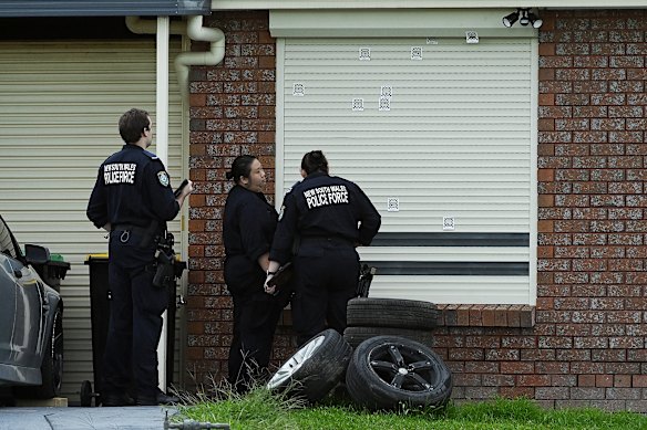 Forensic officers inspect bulletholes at the home in St Clair.