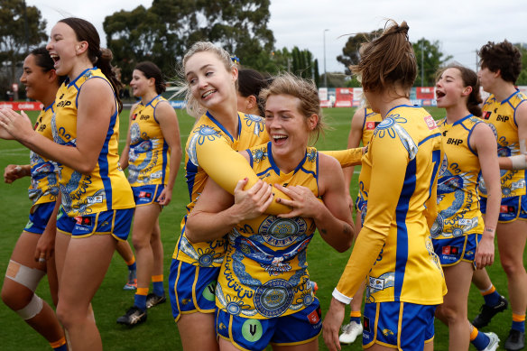 West Coast’s Kate Bartlett (left) and Isabella Lewis celebrate Sunday’s surprise win over Essendon flanked by their teammates.