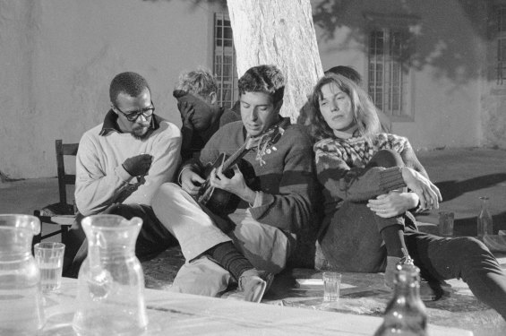 Charmian Clift and American poet Charles Heckstall listen as Leonard Cohen plays guitar in Hydra in October 1960.